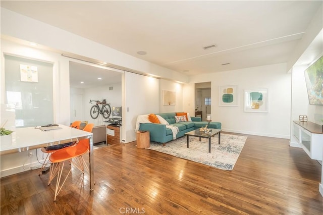 living area featuring visible vents, baseboards, and wood finished floors