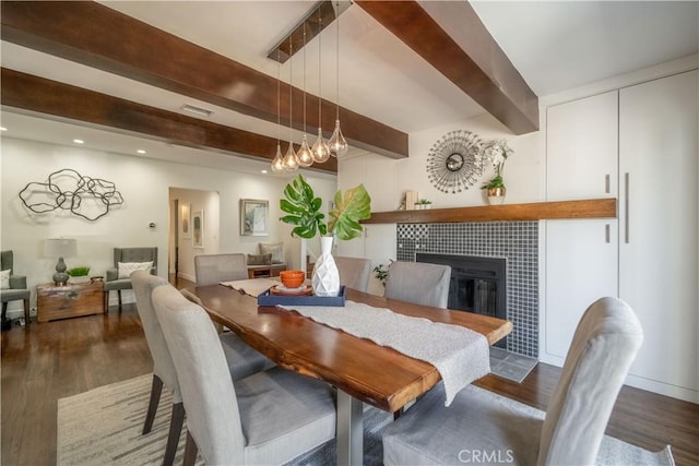 dining area featuring recessed lighting, dark wood-type flooring, a fireplace, visible vents, and beamed ceiling