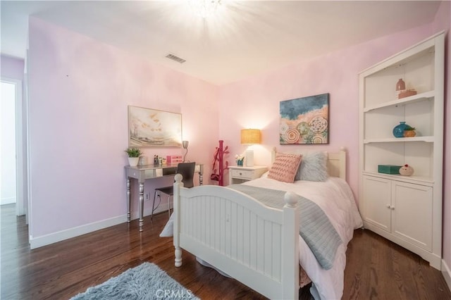 bedroom with baseboards, visible vents, and wood finished floors