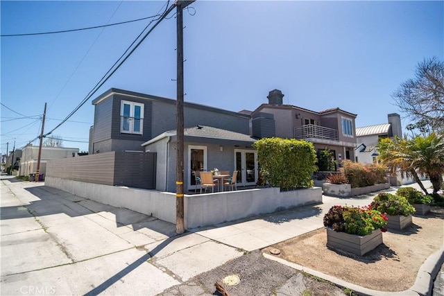 view of front of home with french doors, fence, and stucco siding