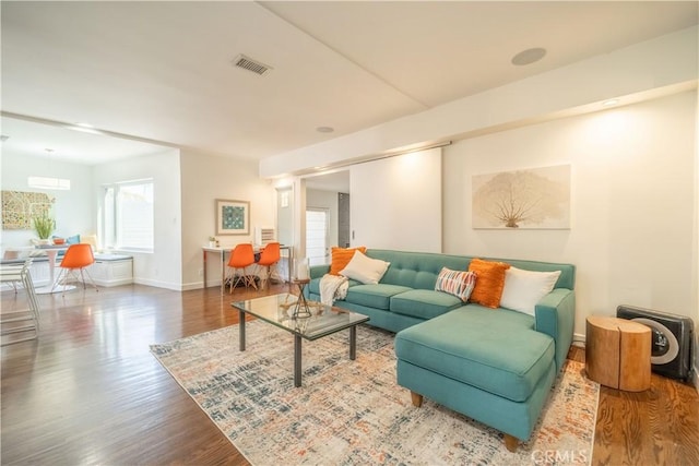 living area featuring visible vents, baseboards, and wood finished floors