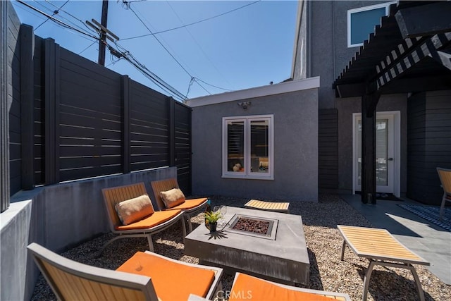 view of patio with fence and an outdoor living space with a fire pit