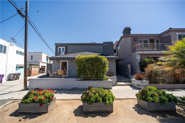 view of front of home with a patio area, a garden, fence, and stucco siding