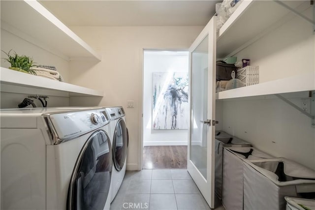 washroom with washing machine and dryer, laundry area, baseboards, and light tile patterned floors