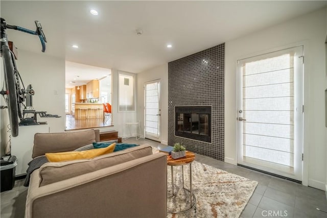 tiled living area featuring baseboards, a tiled fireplace, a wealth of natural light, and recessed lighting