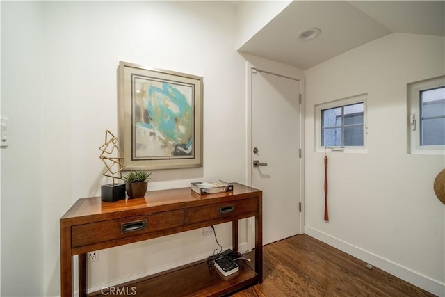 doorway with lofted ceiling, dark wood-type flooring, and baseboards