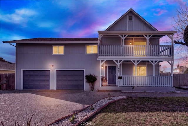 view of front of property with a balcony, fence, driveway, a porch, and a garage