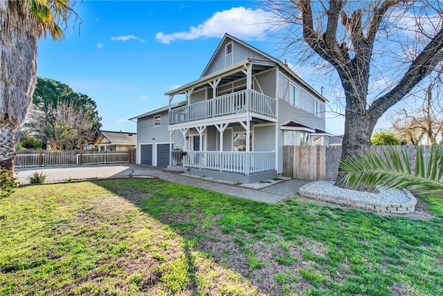 back of property with fence, a porch, a yard, a balcony, and an attached garage