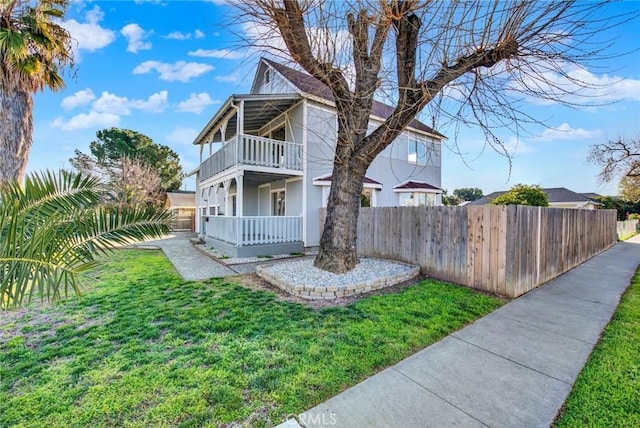 view of front of home featuring a porch, a front yard, a balcony, and fence