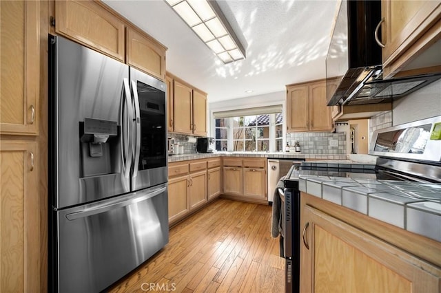 kitchen featuring electric range oven, backsplash, stainless steel fridge, and tile counters