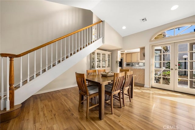 dining room featuring french doors, recessed lighting, light wood-style flooring, high vaulted ceiling, and stairs