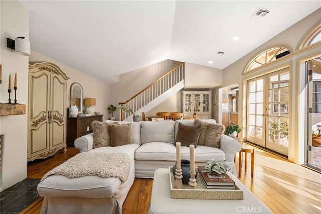 living room with french doors, visible vents, stairway, vaulted ceiling, and wood finished floors