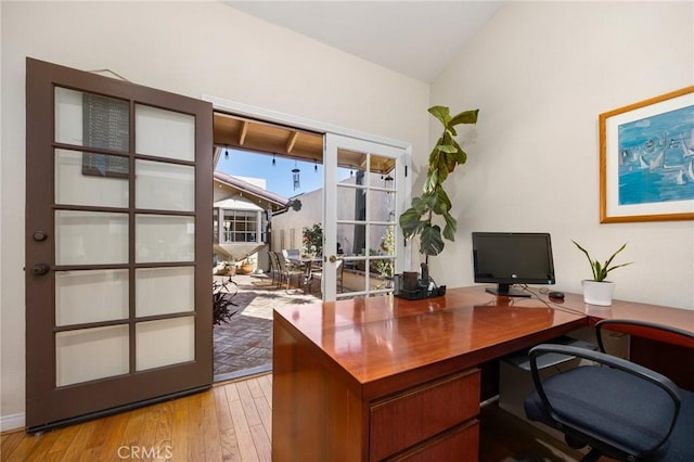 home office featuring light wood-type flooring, french doors, and lofted ceiling