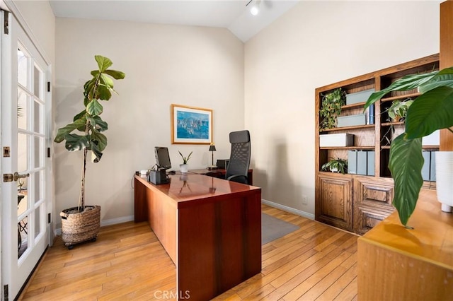 office featuring light wood-style floors, baseboards, and vaulted ceiling