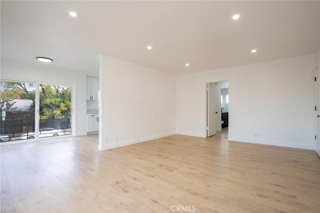 empty room with baseboards, recessed lighting, and light wood-style floors