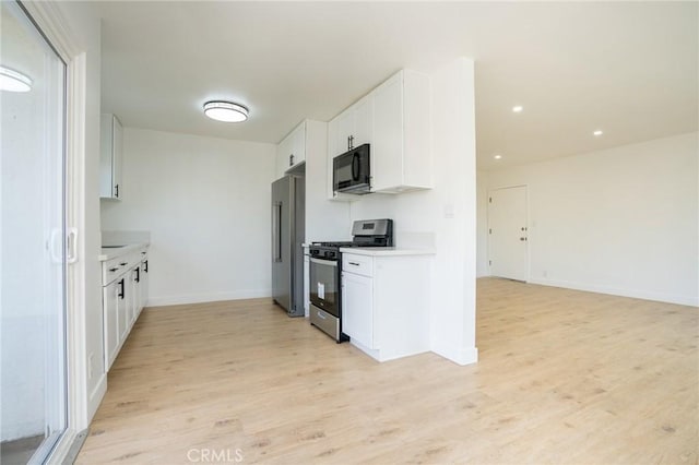 kitchen with stainless steel appliances, light wood finished floors, light countertops, and white cabinets