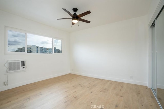 spare room featuring light wood-style floors, ceiling fan, baseboards, and a wall mounted AC