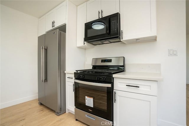 kitchen with baseboards, white cabinets, light wood-style flooring, appliances with stainless steel finishes, and light countertops