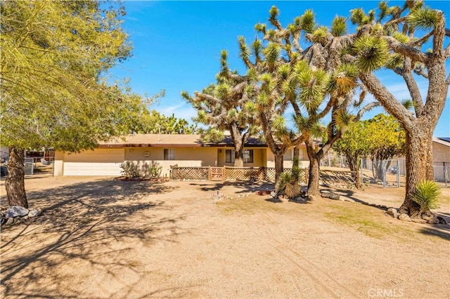 ranch-style house with a garage, fence, and stucco siding