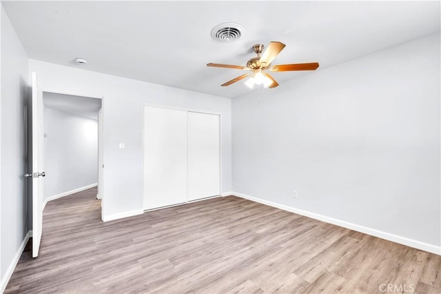 unfurnished bedroom featuring a closet, visible vents, ceiling fan, wood finished floors, and baseboards