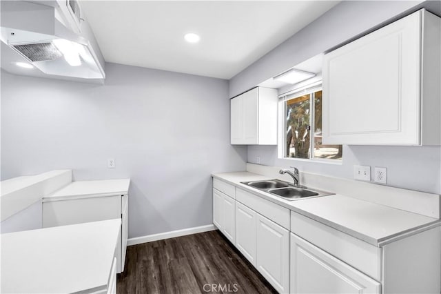 kitchen with dark wood-style flooring, light countertops, white cabinetry, a sink, and baseboards