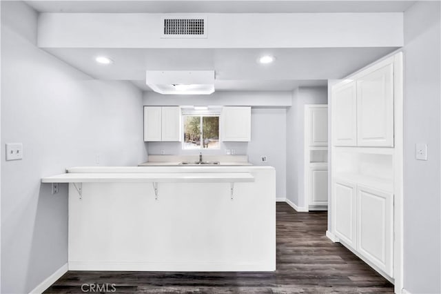 kitchen featuring a sink, baseboards, visible vents, and a breakfast bar area