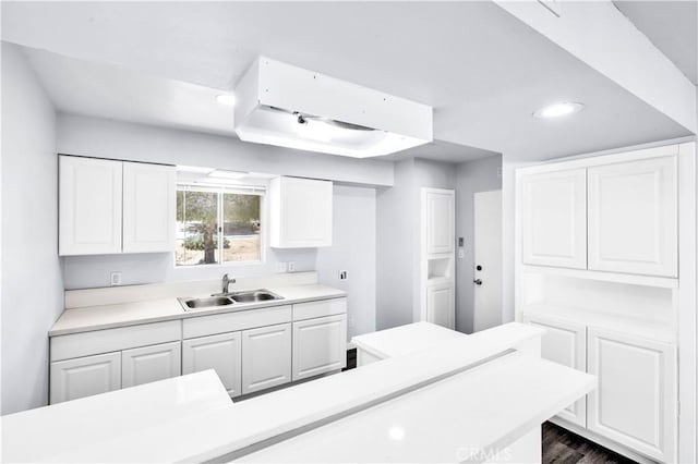 kitchen featuring dark wood-type flooring, light countertops, white cabinetry, and a sink