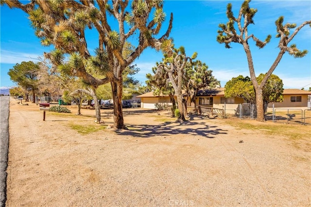 view of yard featuring a gate, dirt driveway, and fence