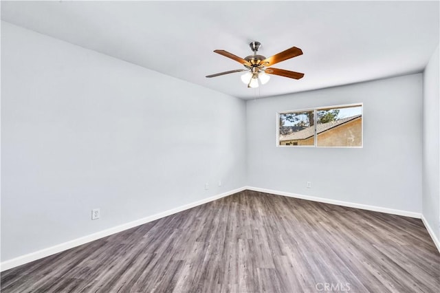 empty room featuring a ceiling fan, dark wood-style flooring, and baseboards