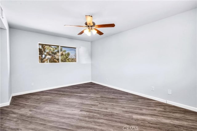 unfurnished room with ceiling fan, dark wood finished floors, and baseboards