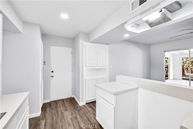 corridor featuring dark wood-type flooring, recessed lighting, visible vents, and baseboards