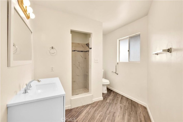 full bathroom featuring baseboards, toilet, wood finished floors, vanity, and a shower stall