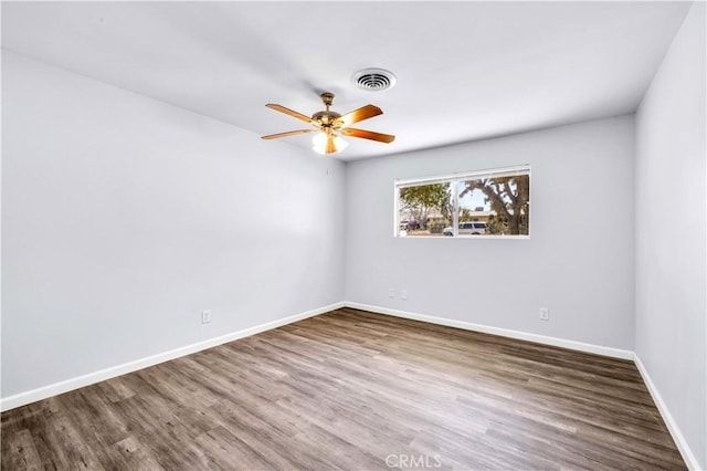 unfurnished room featuring a ceiling fan, visible vents, baseboards, and wood finished floors