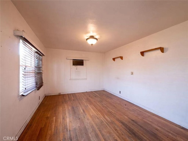 unfurnished room with baseboards and wood finished floors