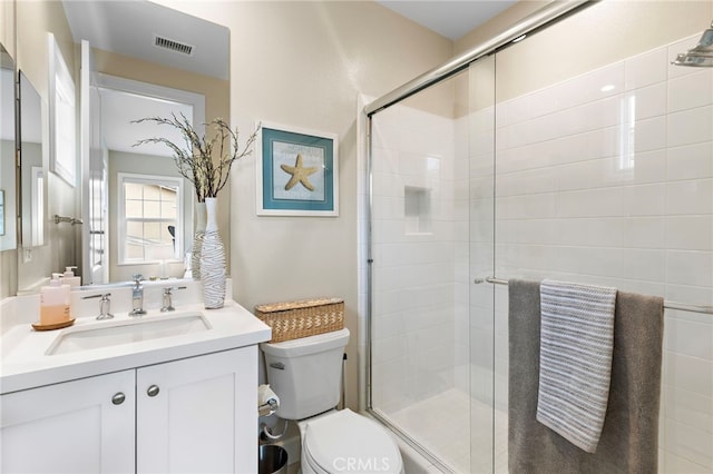 full bathroom featuring vanity, a shower stall, toilet, and visible vents