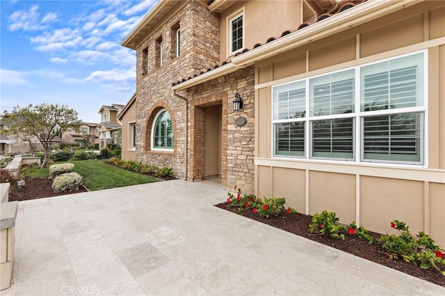 exterior space featuring stone siding, stucco siding, and a yard