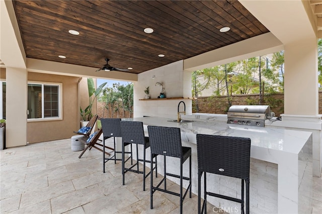 view of patio / terrace with a sink, fence, grilling area, outdoor wet bar, and exterior kitchen