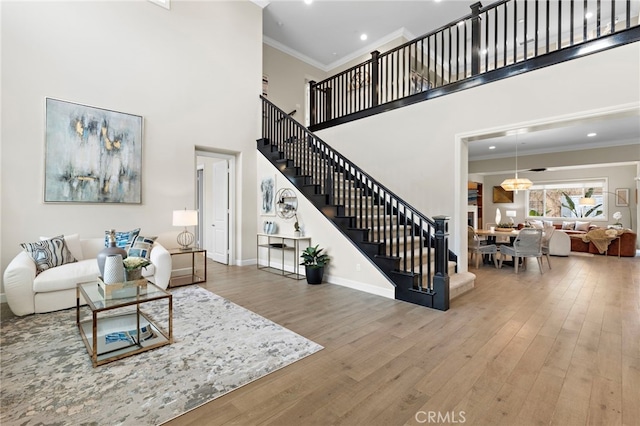 living room with stairway, crown molding, a high ceiling, and wood finished floors