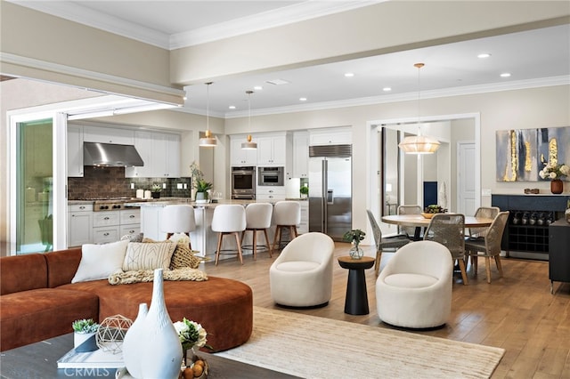 living room with light wood finished floors, recessed lighting, and ornamental molding