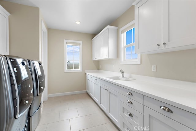 laundry area with baseboards, washing machine and dryer, light tile patterned flooring, cabinet space, and a sink