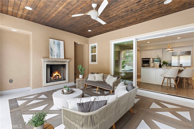 living room with wood ceiling, baseboards, a warm lit fireplace, and recessed lighting