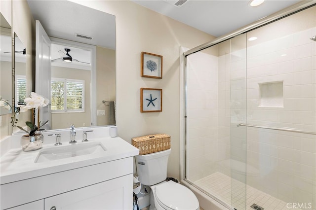 bathroom featuring visible vents, toilet, a stall shower, and vanity