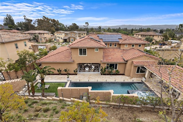 rear view of property featuring solar panels, a fenced backyard, stucco siding, a tiled roof, and a patio area