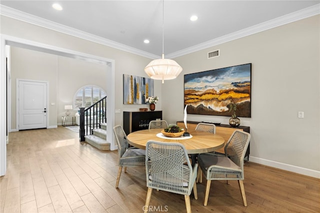 dining area with visible vents, wood finished floors, ornamental molding, and stairs