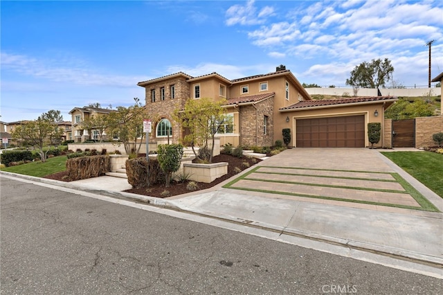 mediterranean / spanish-style house with a gate, an attached garage, stucco siding, concrete driveway, and a tile roof