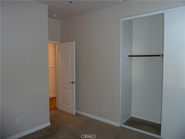 unfurnished bedroom with carpet, a closet, and baseboards