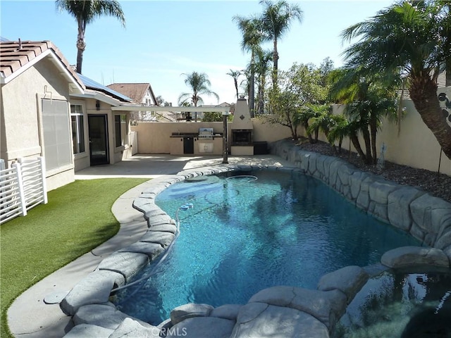 view of swimming pool with exterior kitchen, a patio area, a fenced backyard, and a fenced in pool