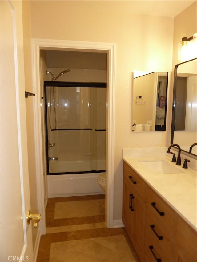 full bath featuring toilet, shower / bath combination with glass door, and vanity