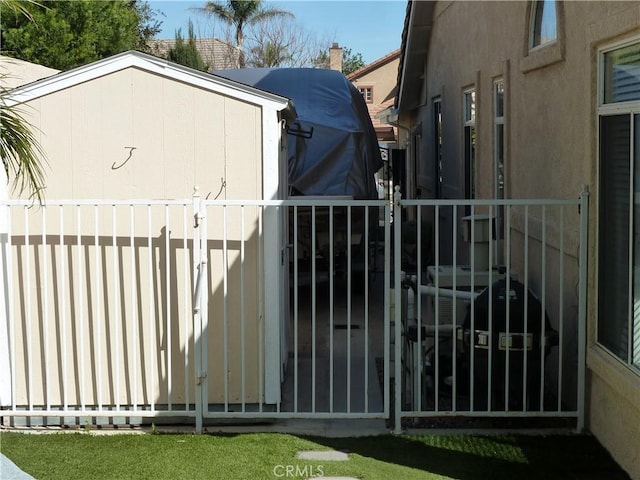 view of gate featuring an outbuilding, a storage unit, and fence