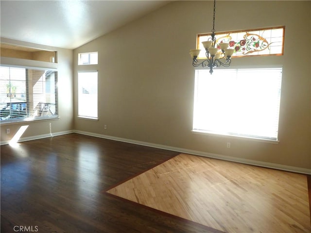 spare room featuring lofted ceiling, baseboards, wood finished floors, and an inviting chandelier